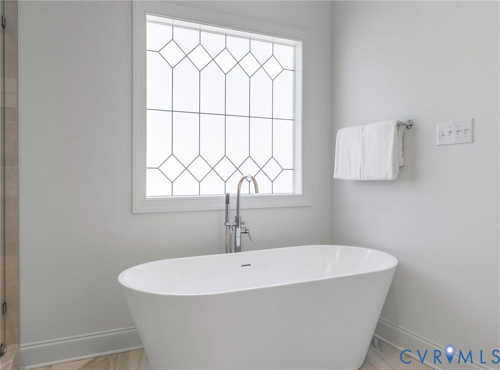 2831 Old Pump Road, The Preserve At John Rolfe, Henrico, VA 23233 Freestanding soaking tub with a floor-mounted polished chrome faucet, leaded glass window, and light-toned walls