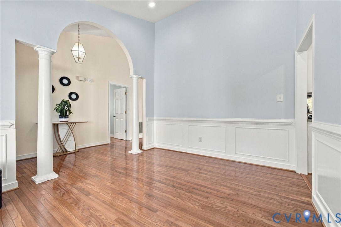 8119 Castle Grove Drive, Mechanicsville, VA 23111 Dining Area, High ceilings featuring an arched opening with columns, hardwood flooring, and wainscoting detailing