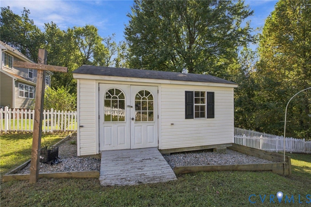 8119 Castle Grove Drive, Mechanicsville, VA 23111 Detached storage shed featuring vinyl siding, dual-arched glass-paneled doors, shuttered window, and gravel-based hardscaping