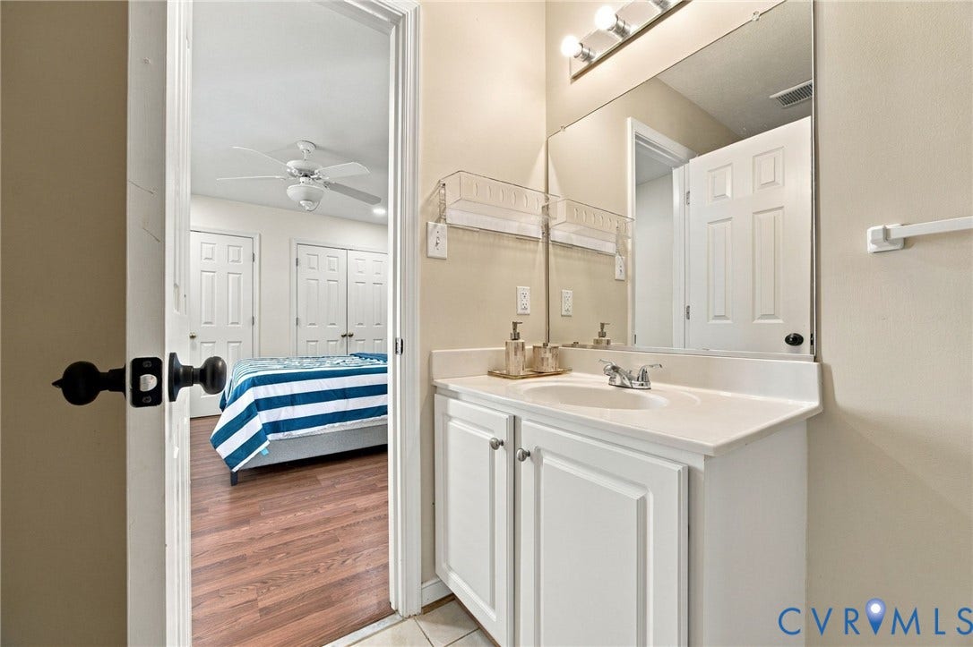 8119 Castle Grove Drive, Mechanicsville, VA 23111 Bathroom Vanity featuring a white cabinetry base, integrated countertop and sink, chrome dual-handle faucet, full-width wall mirror, and overhead tri-light fixture