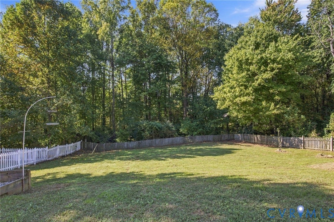 8119 Castle Grove Drive, Mechanicsville, VA 23111 Expansive backyard featuring a level lawn, white picket fencing, wood-slat perimeter fencing, and mature trees