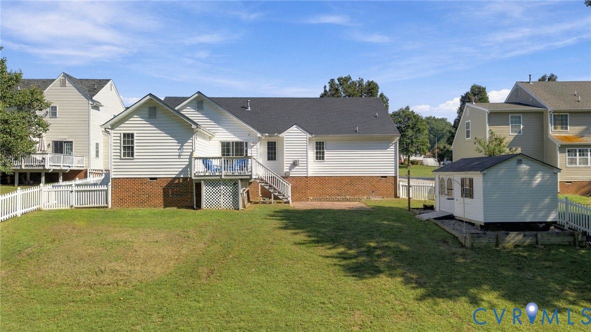 8119 Castle Grove Drive, Mechanicsville, VA 23111 Backyard featuring a vinyl siding exterior with brick foundation, an elevated deck with lattice skirting, a detached storage shed, and a perimeter picket fence