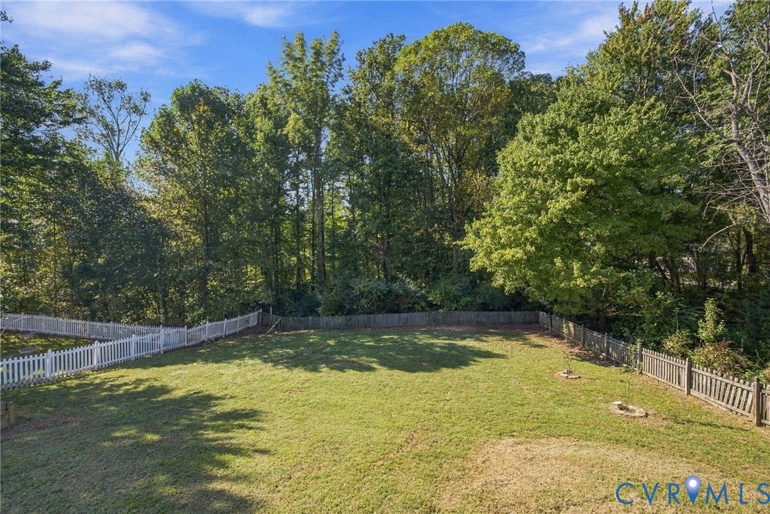 8119 Castle Grove Drive, Mechanicsville, VA 23111 Expansive backyard featuring a level lawn, white picket fencing, wood-slat perimeter fencing, and mature trees