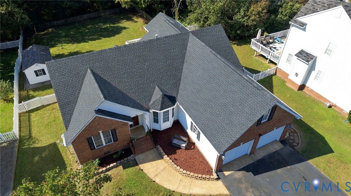 8119 Castle Grove Drive, Mechanicsville, VA 23111 Aerial perspective of a multi-gabled brick and siding residence featuring a two-car garage, asphalt shingle roof, curved hardscape walkway, and an external storage structure