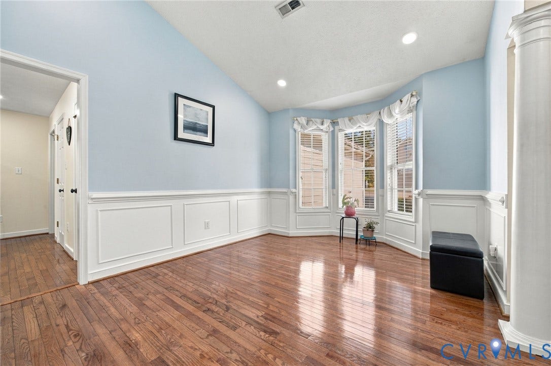 8119 Castle Grove Drive, Mechanicsville, VA 23111 Dining Area, High ceilings featuring an arched opening with columns, hardwood flooring, and wainscoting detailing