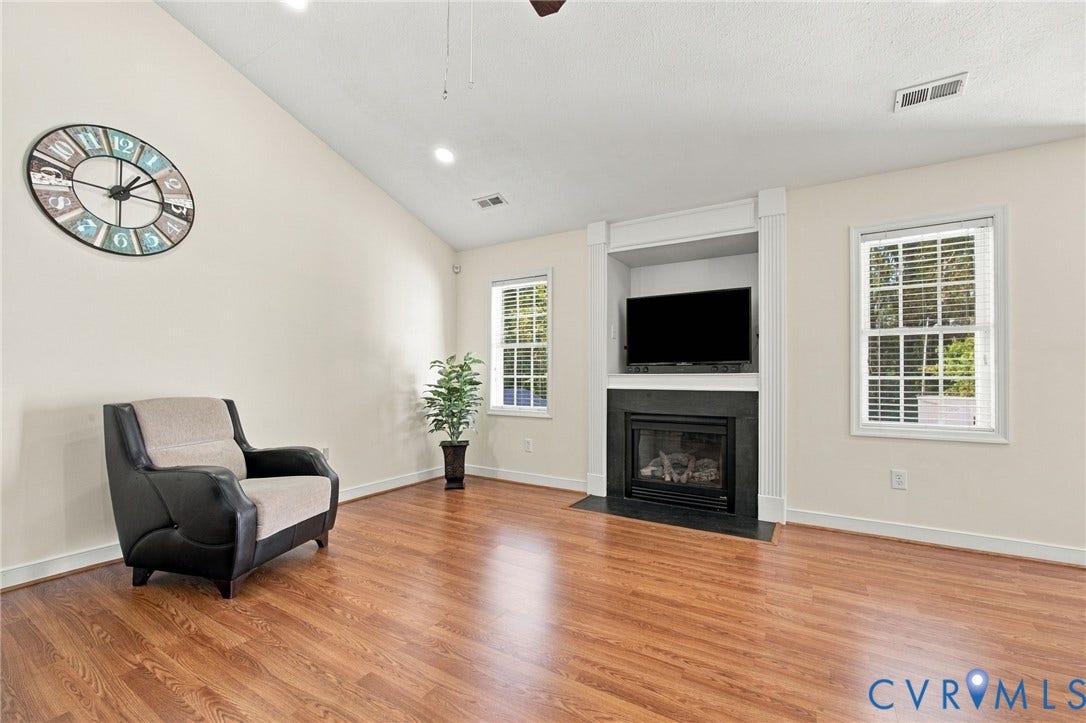 8119 Castle Grove Drive, Mechanicsville, VA 23111 Living room with Vaulted ceilings, wood-finish flooring, built-in entertainment niche, and fireplace with black surround