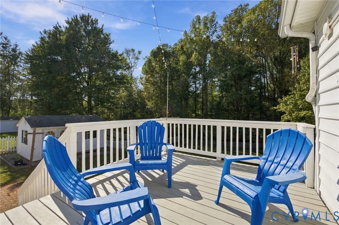 8119 Castle Grove Drive, Mechanicsville, VA 23111 Elevated wooden deck featuring white railing and string lighting, overlooking a private backyard with a storage shed