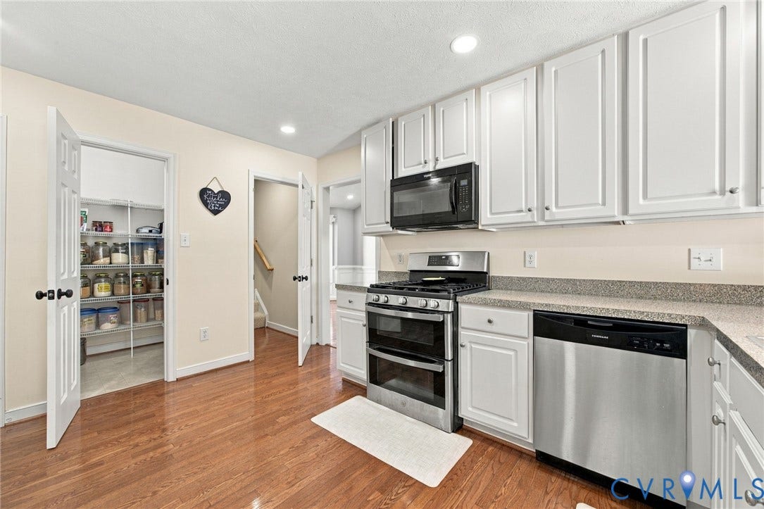 8119 Castle Grove Drive, Mechanicsville, VA 23111 Kitchen featuring white shaker-style cabinetry, wood-finish flooring, stone-composite countertops, stainless steel appliances, and a walk-in pantry
