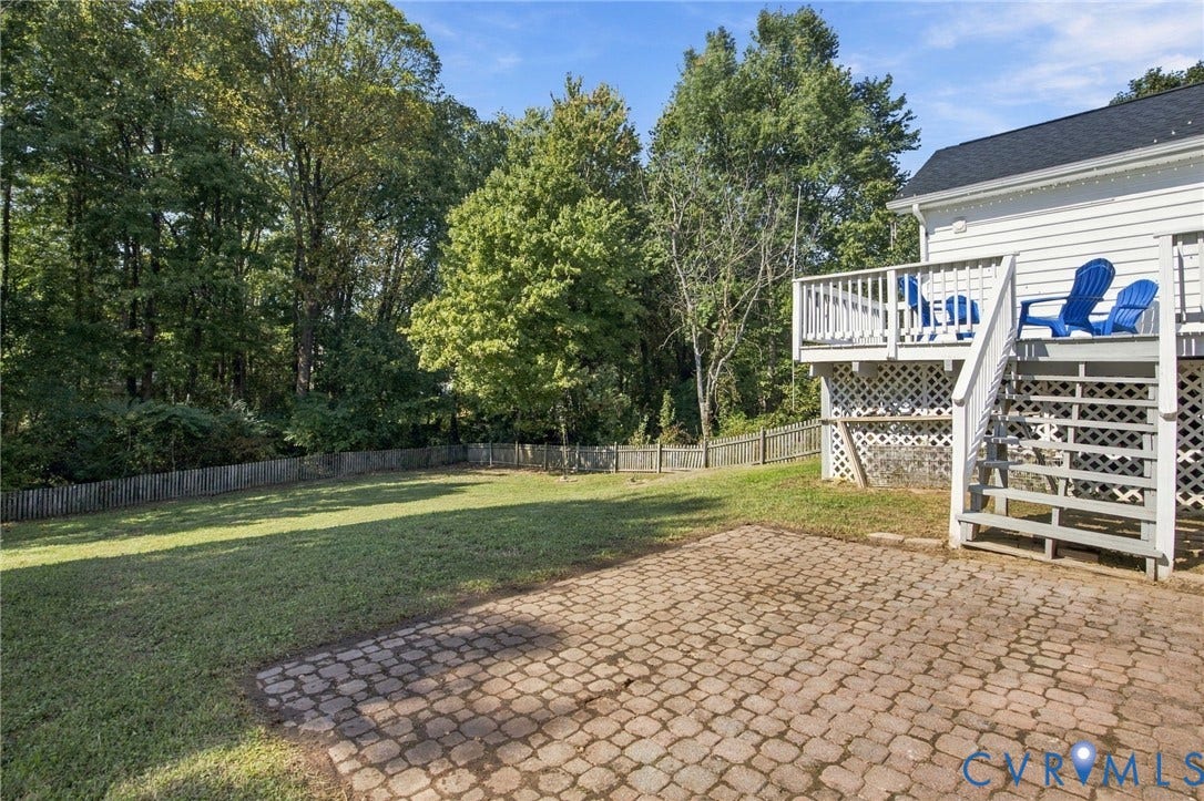 8119 Castle Grove Drive, Mechanicsville, VA 23111 Backyard featuring a stone paver patio, elevated deck with railing, lattice under-deck skirting, and wood-fenced perimeter