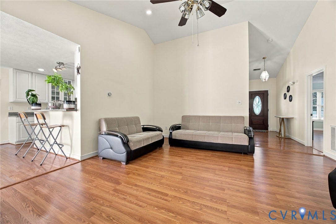 8119 Castle Grove Drive, Mechanicsville, VA 23111 Living Room with Vaulted ceilings featuring a multi-blade ceiling fan, wood-finish flooring, and a pass-through opening to the kitchen area