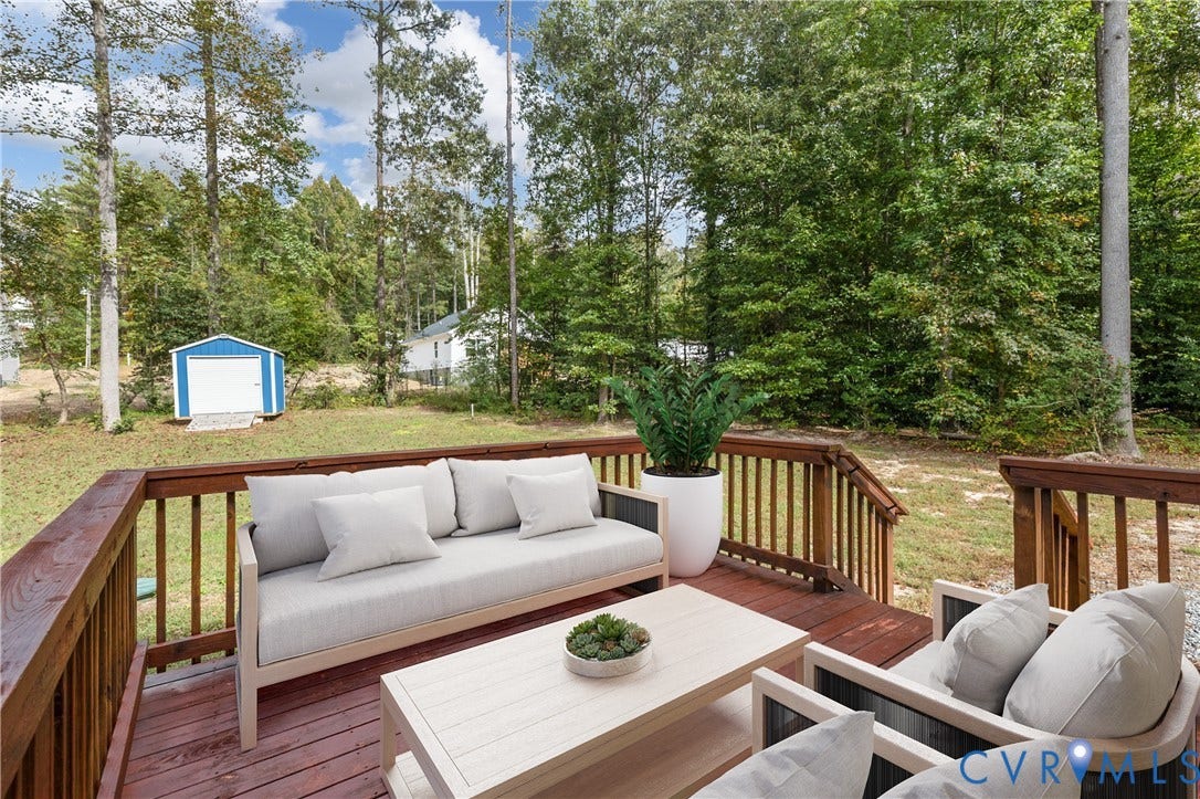 12089 Monterey Road, Ruther Glen, VA 22546 Elevated wooden deck with balustrade railings overlooking a partially wooded lot featuring a detached storage structure