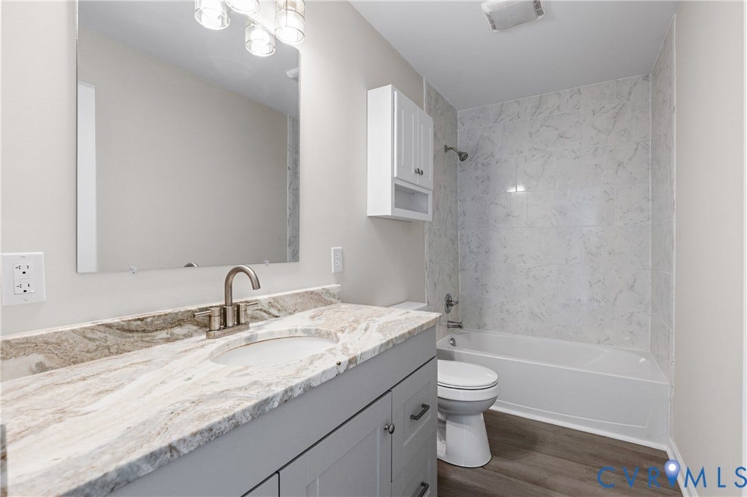 12089 Monterey Road, Ruther Glen, VA 22546 Bathroom featuring a grey vanity with stone countertop, an integrated sink, a large wall-mounted mirror, and a tub-shower combination with surround tile