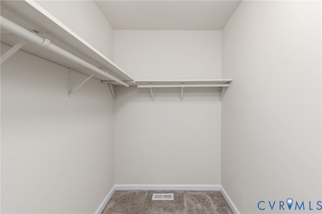 12089 Monterey Road, Ruther Glen, VA 22546 Walk-in storage space featuring neutral wall paint, wall-to-wall carpeting, and wrap-around shelving with integrated garment rods