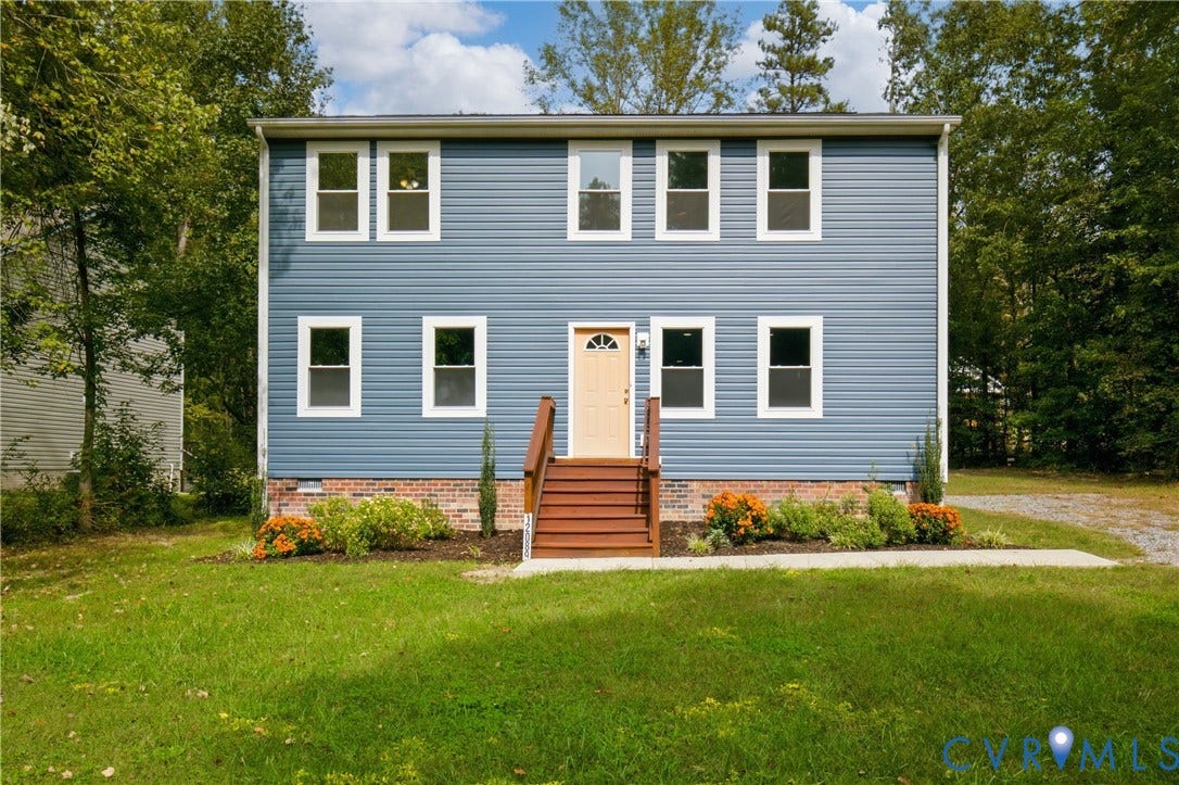 12089 Monterey Road, Ruther Glen, VA 22546 Two-story home featuring blue horizontal siding, a red brick foundation, a centered wooden staircase with handrails, and a multi-pane glass entry door