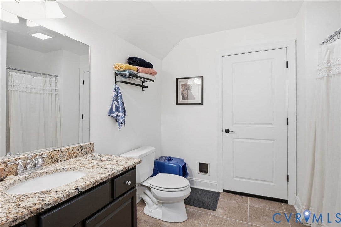 4502 Jennway Turn, Summer Lake, Moseley, VA 23120 Dark-finished vanity with a stone-top integrated sink, large wall-mounted mirror, ceramic tile flooring, and a two-panel interior door