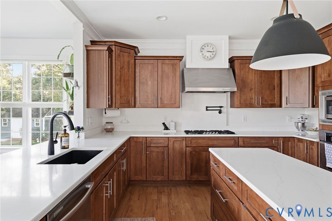 4502 Jennway Turn, Summer Lake, Moseley, VA 23120 Kitchen featuring stained wood cabinetry, stone countertops, a stainless steel gas range with a matching wall-mounted hood, and an oversized black pendant light fixture