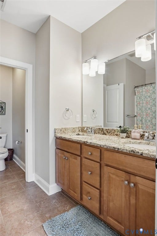 4502 Jennway Turn, Summer Lake, Moseley, VA 23120 Bathroom featuring a dual-sink vanity with stone-finish countertops, wood-finish cabinetry, a large wall-mounted mirror, and ceramic tile flooring