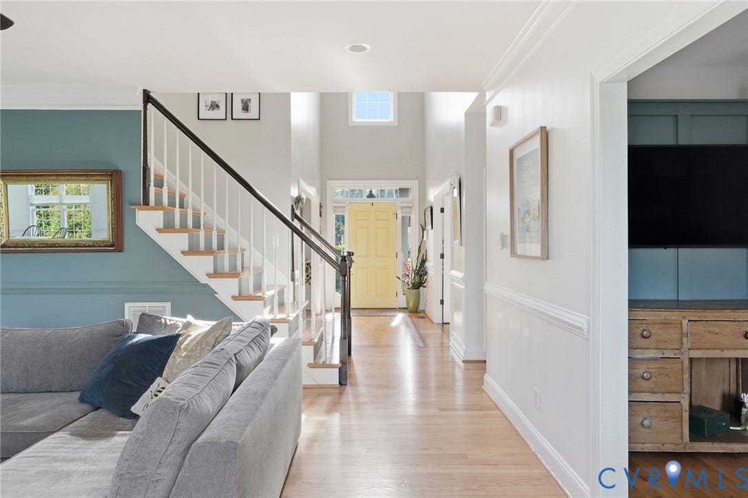 4502 Jennway Turn, Summer Lake, Moseley, VA 23120 Foyer featuring wood-finish flooring, a staircase with a dark wood handrail, high ceilings with a transom window, and paneled wainscoting