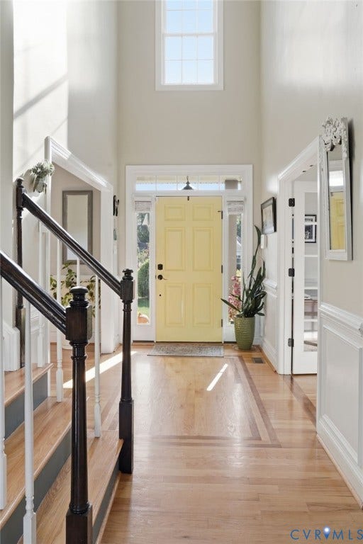 4502 Jennway Turn, Summer Lake, Moseley, VA 23120 Entryway featuring a two-story ceiling with high-elevation window, wood-finish flooring with inlaid border, staircase with dark wood-finish railing, and a paneled door with glass side-lights