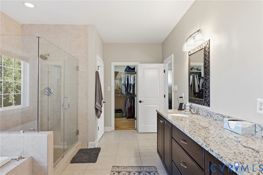 4502 Jennway Turn, Summer Lake, Moseley, VA 23120 Bathroom featuring a glass-enclosed shower, stone-surfaced vanity with dual sinks, dark-finish cabinetry, and ceramic tile flooring