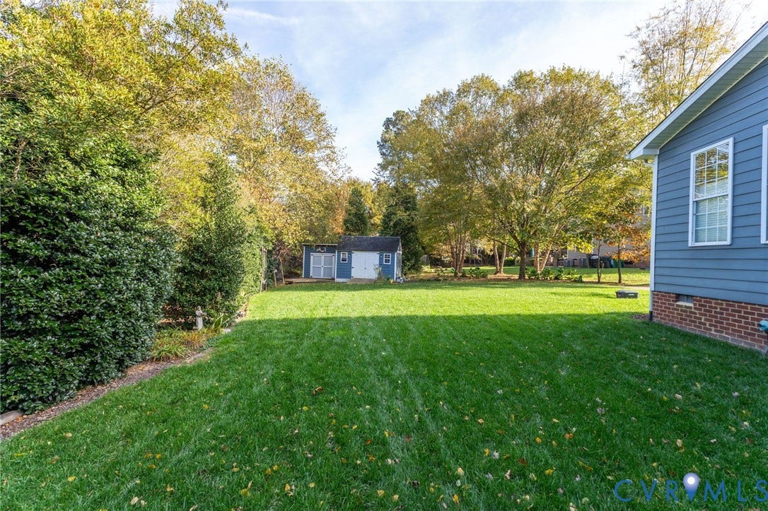 4502 Jennway Turn, Summer Lake, Moseley, VA 23120 Expansive backyard featuring a level lawn, mature trees, a detached storage building, and horizontal lap siding with a brick foundation