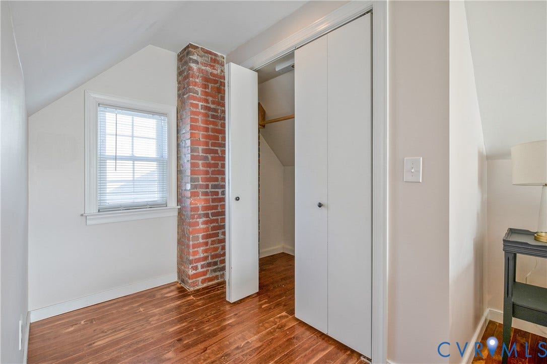 3006 Porter Street, Richmond, VA 23225 Exposed brick chimney element, wood-finish flooring, and closet with bifold doors under a sloped ceiling