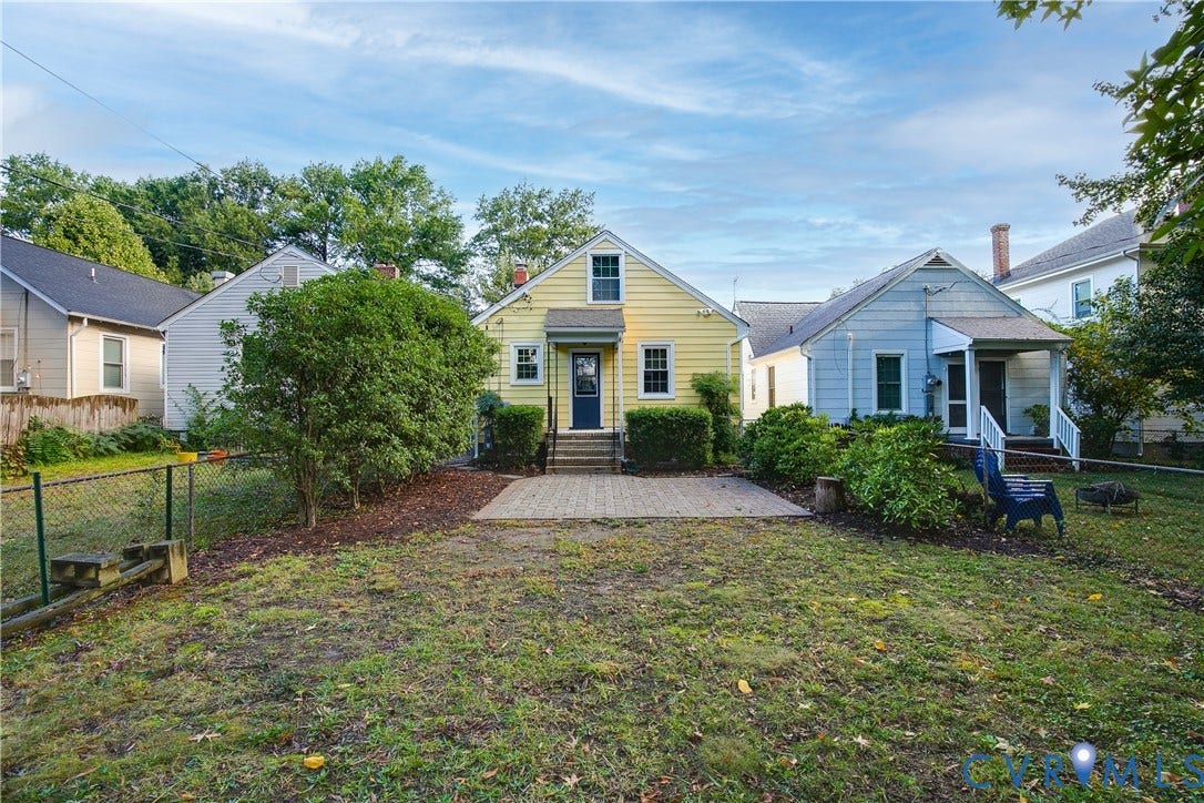 3006 Porter Street, Richmond, VA 23225 Yellow siding exterior featuring a paved stone patio, a chain-link fenced perimeter, and mature landscaping