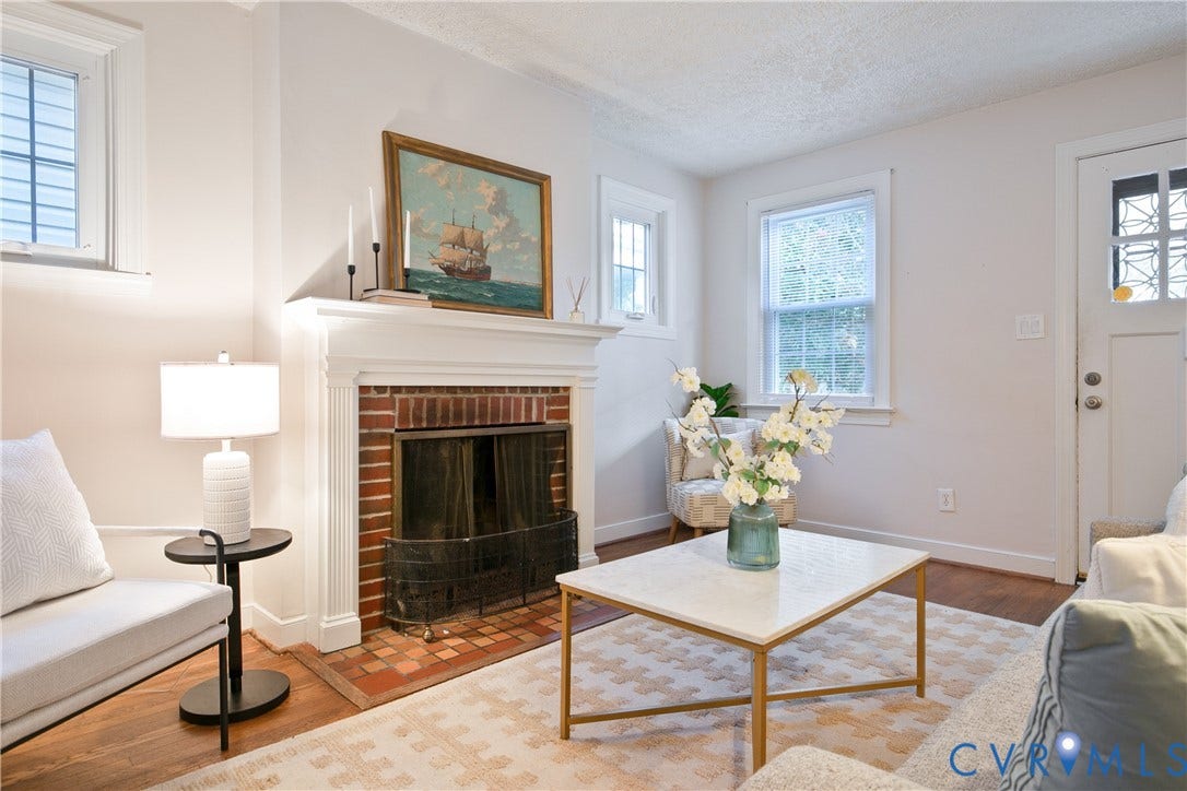 3006 Porter Street, Richmond, VA 23225 Fireplace featuring a classic red brick surround, a decorative white mantel with fluted pilasters, and a matching brick hearth, paired with wood-finish flooring and multi-pane windows