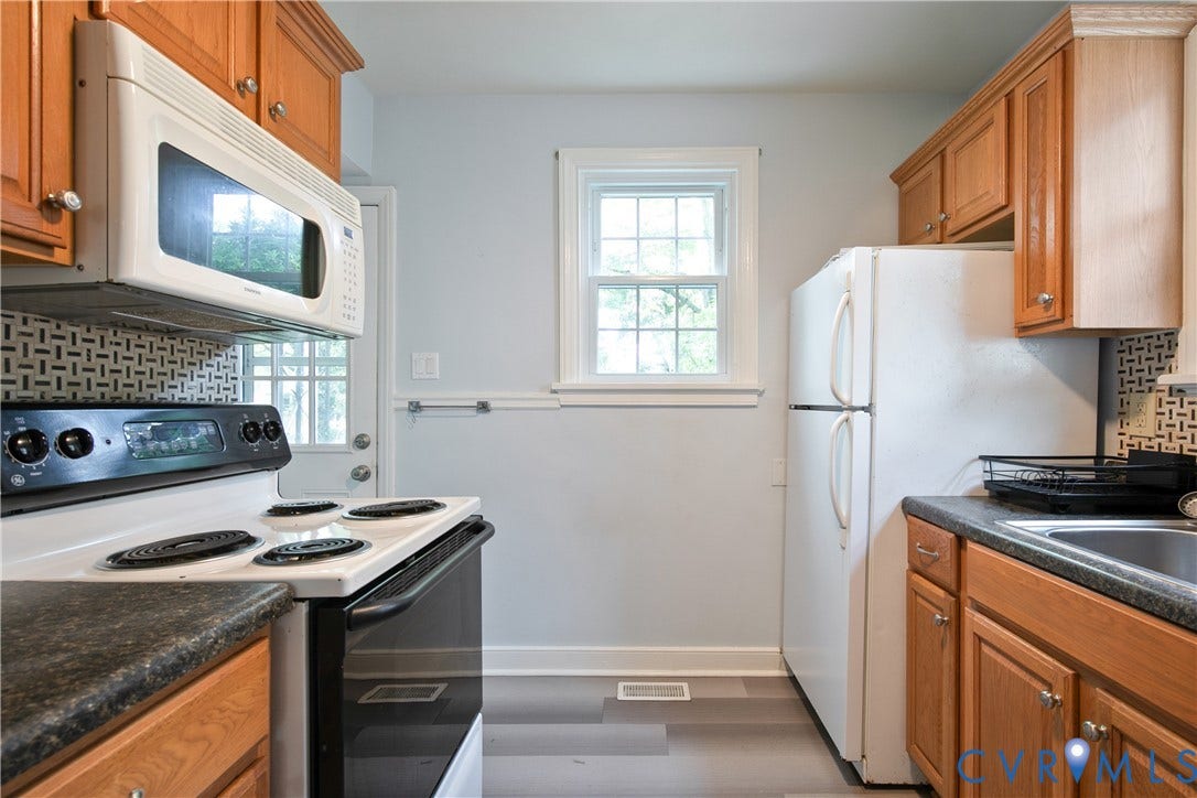 3006 Porter Street, Richmond, VA 23225 Kitchen featuring wood cabinetry, laminate countertops, a geometric-pattern tile backsplash, and wood-finish flooring