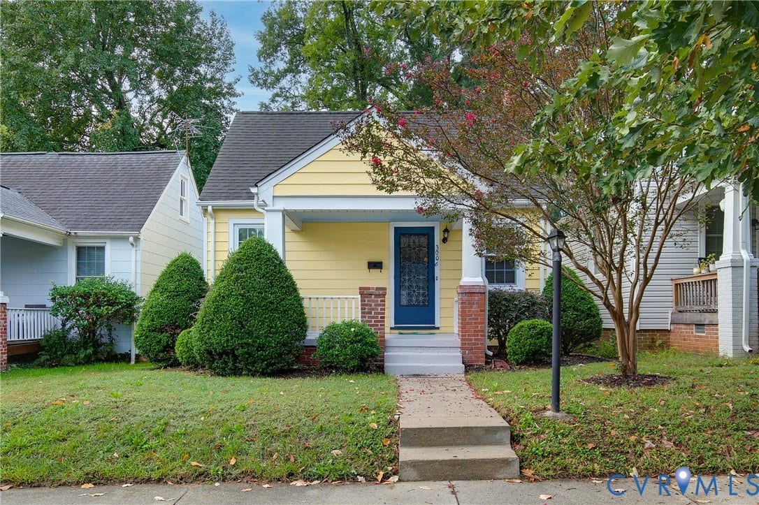 3006 Porter Street, Richmond, VA 23225 Exterior featuring pale yellow siding, a covered front porch with brick column accents, a concrete walkway, and a roofline with a decorative gable