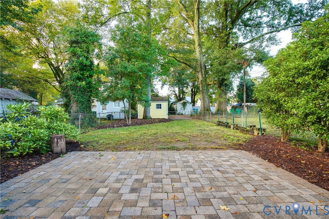 3006 Porter Street, Richmond, VA 23225 Paver patio featuring a rectangular grid pattern, expansive lawn, mature shade trees, and a detached storage structure