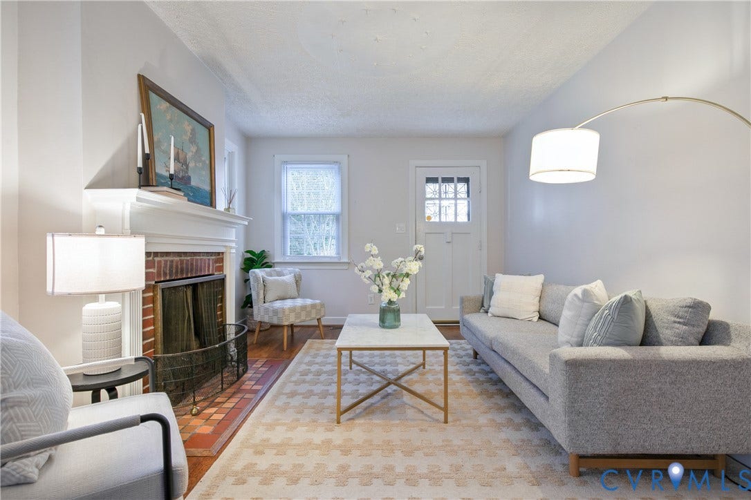 3006 Porter Street, Richmond, VA 23225 Living area featuring a brick fireplace with a decorative mantel, terracotta-style hearth tiling, multi-pane entry door, and neutral wall tones