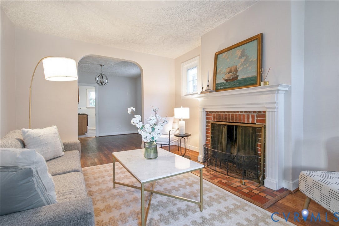 3006 Porter Street, Richmond, VA 23225 Living area featuring a fireplace with a traditional brick surround, a painted wooden mantel, wood-finish flooring, and a distinctive arched doorway
