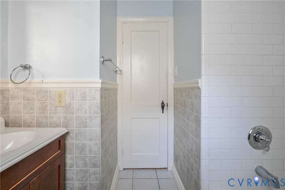 3006 Porter Street, Richmond, VA 23225 Bathroom featuring a wood-finish vanity, square tile wainscoting, white subway tile shower surround, and a chrome faucet fixture