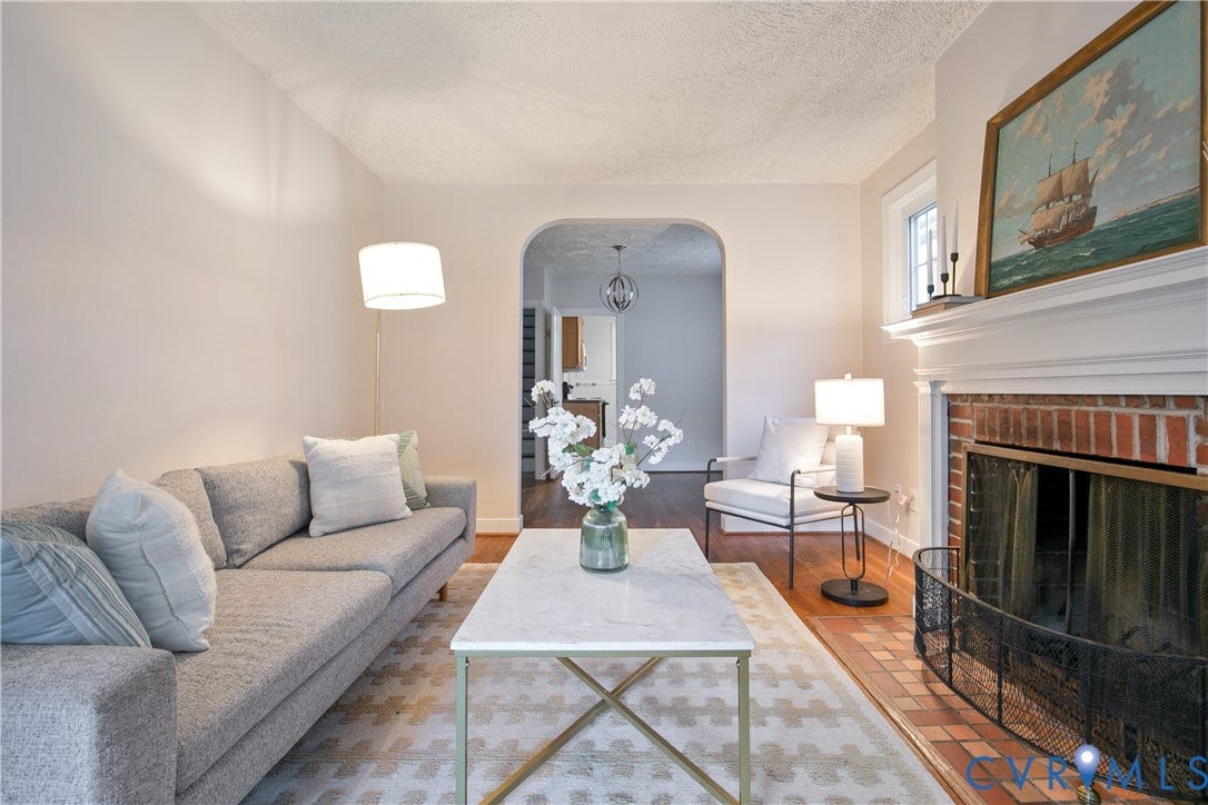 3006 Porter Street, Richmond, VA 23225 Living area featuring a red brick fireplace, a prominent white mantel, arched architectural detail, and wood-finish flooring