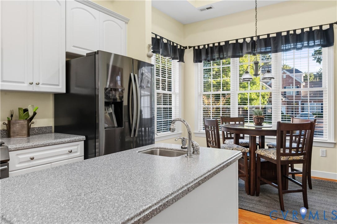 3360 Manor Grove Circle, Glen Allen, VA 23059 Kitchen featuring white cabinetry, solid-surface countertops, center island with integrated stainless steel sink, and stainless steel refrigerator