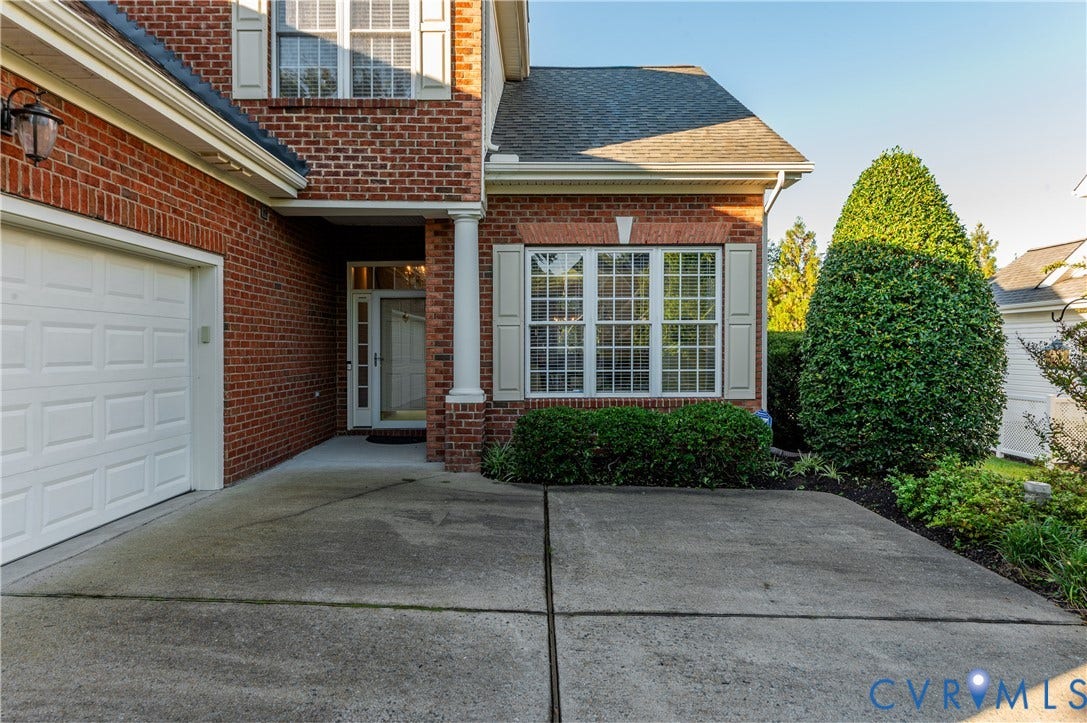 3360 Manor Grove Circle, Glen Allen, VA 23059 Traditional brick exterior featuring a multi-panel garage door, classic grid-pane windows with shutters, and a covered entry with a white column