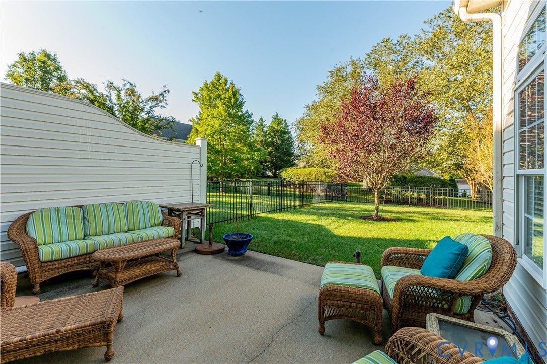 3360 Manor Grove Circle, Glen Allen, VA 23059 Concrete patio featuring horizontal vinyl siding, a privacy wall, and a metal perimeter fence surrounding a grass lawn
