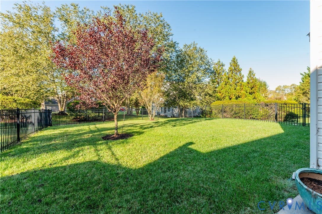 3360 Manor Grove Circle, Glen Allen, VA 23059 Backyard featuring a manicured lawn, perimeter black metal fencing, and established trees