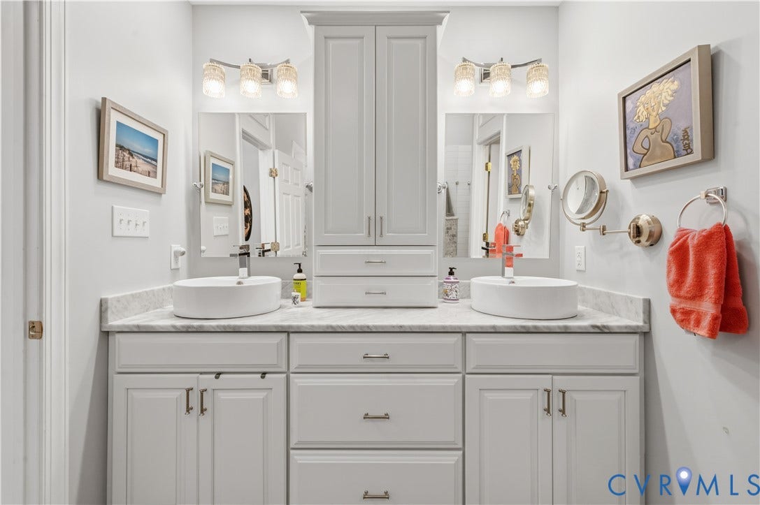 3360 Manor Grove Circle, Glen Allen, VA 23059 Dual-sink vanity featuring stone countertops, two oval vessel sinks, a central storage tower, and three-light decorative fixtures