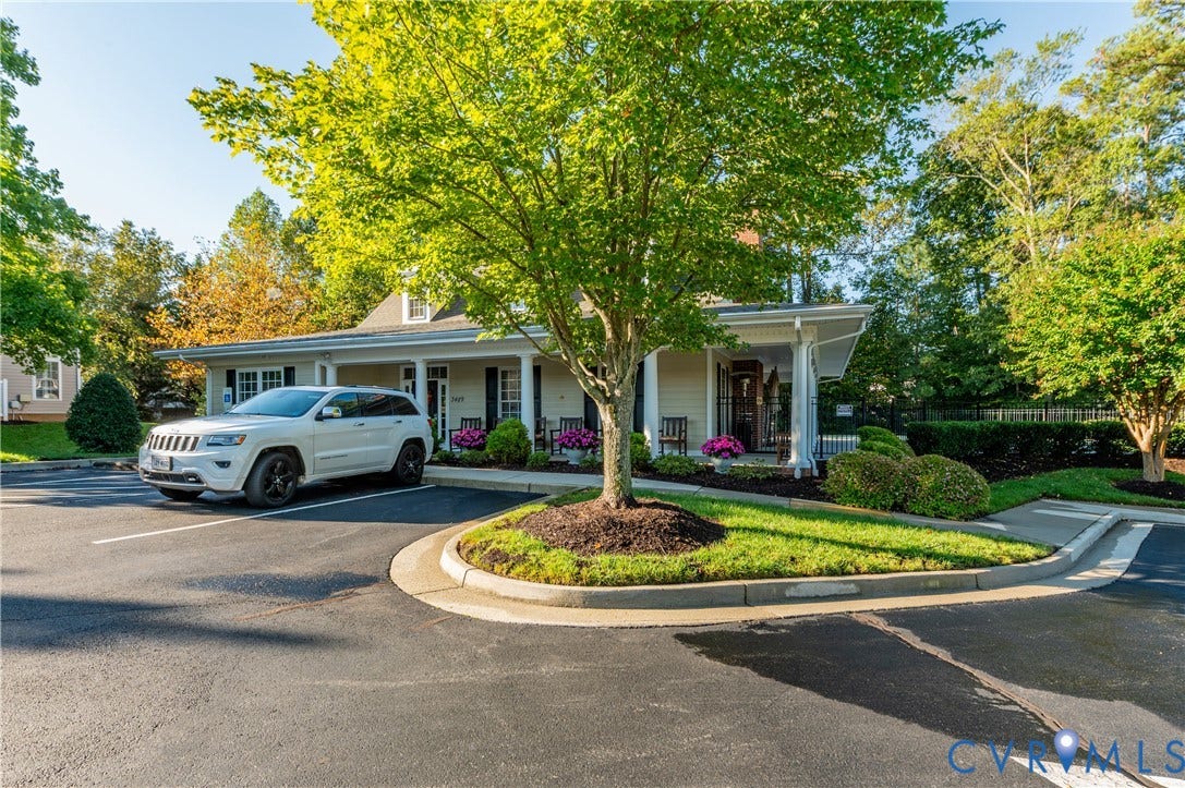 3360 Manor Grove Circle, Glen Allen, VA 23059 Single-story exterior featuring light-colored siding, a covered porch with structural columns, and paved parking area with landscaped lawn islands and mature trees