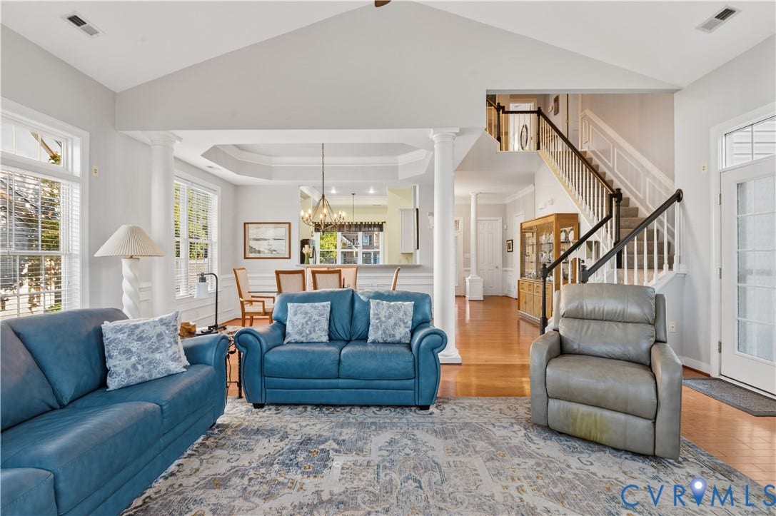 3360 Manor Grove Circle, Glen Allen, VA 23059 Vaulted ceiling featuring structural columns, tray ceiling detail, hardwood flooring, and a staircase with a wooden handrail