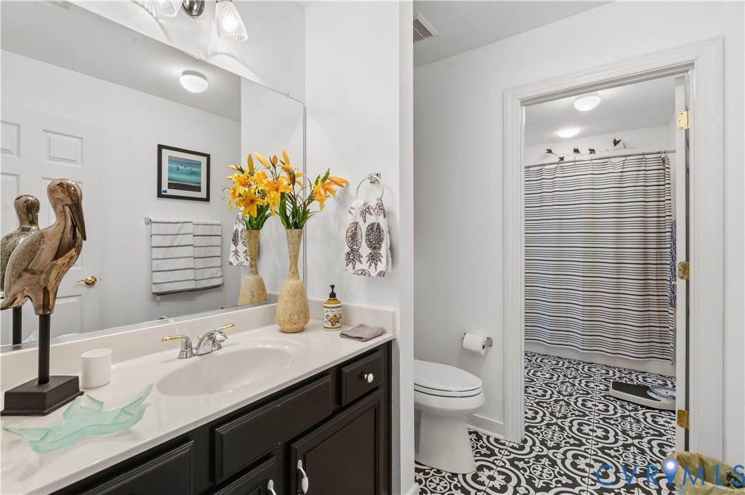 3360 Manor Grove Circle, Glen Allen, VA 23059 Bathroom featuring a dark-toned vanity, white countertop with an integrated oval sink, polished metal faucet, and patterned floor tile