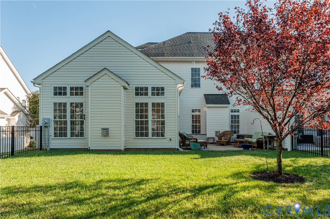 3360 Manor Grove Circle, Glen Allen, VA 23059 Rear exterior featuring light-toned horizontal siding, multi-pane windows, a paved patio area, and a metal perimeter fence