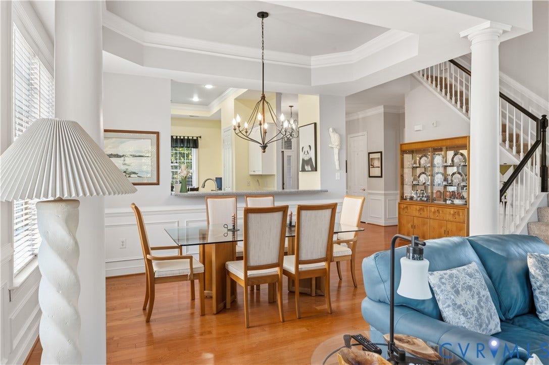 3360 Manor Grove Circle, Glen Allen, VA 23059 Tray ceiling with decorative crown molding, architectural support columns, wood-finish flooring, metal multi-light chandelier, and wainscoting detailing