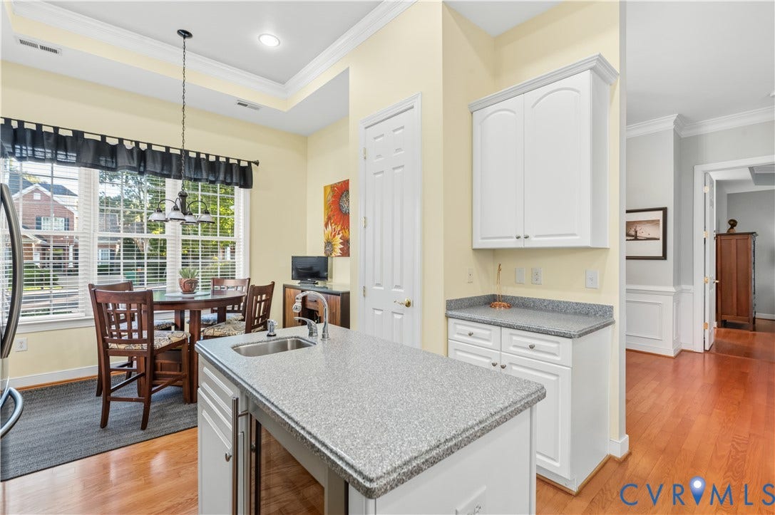 3360 Manor Grove Circle, Glen Allen, VA 23059 Kitchen featuring a central island with an integrated sink, white cabinetry, stone-finish countertops, tray ceiling, and wood-finish flooring