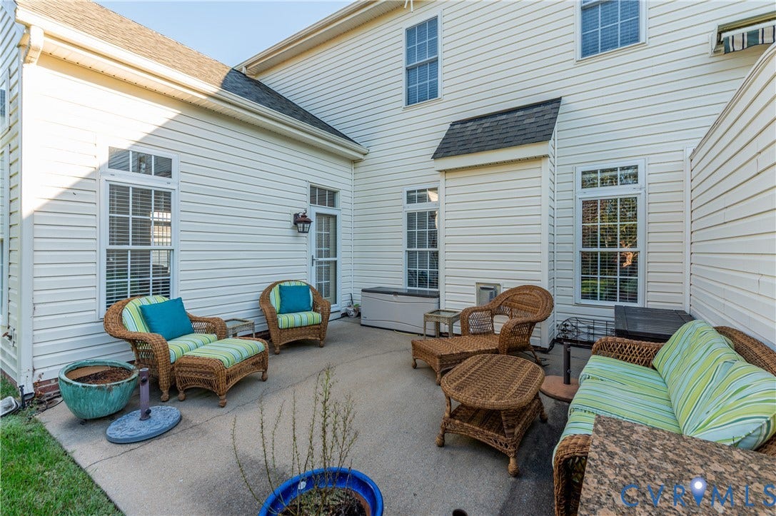 3360 Manor Grove Circle, Glen Allen, VA 23059 Concrete patio enclosed by light-colored horizontal siding, multiple multi-pane windows, and a dedicated exterior light fixture
