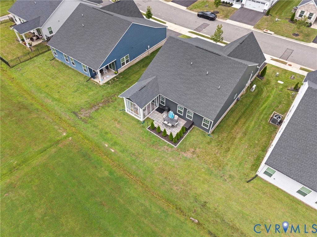 Exterior features include a dark-toned siding, a screened-in porch, a paved stone patio, and a manicured lawn