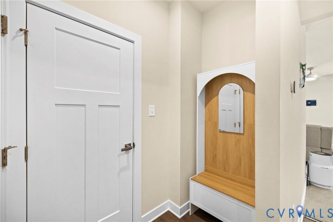 Built-in wood-finish entry bench featuring an arched wooden back panel, integrated mirror, and white cabinetry