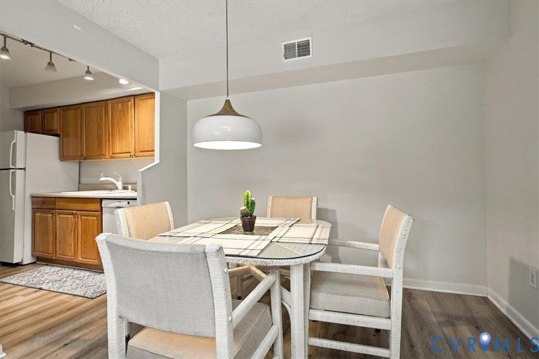 Wood-finish flooring, mid-tone wood cabinetry, white kitchen appliances, and a modern dome pendant light